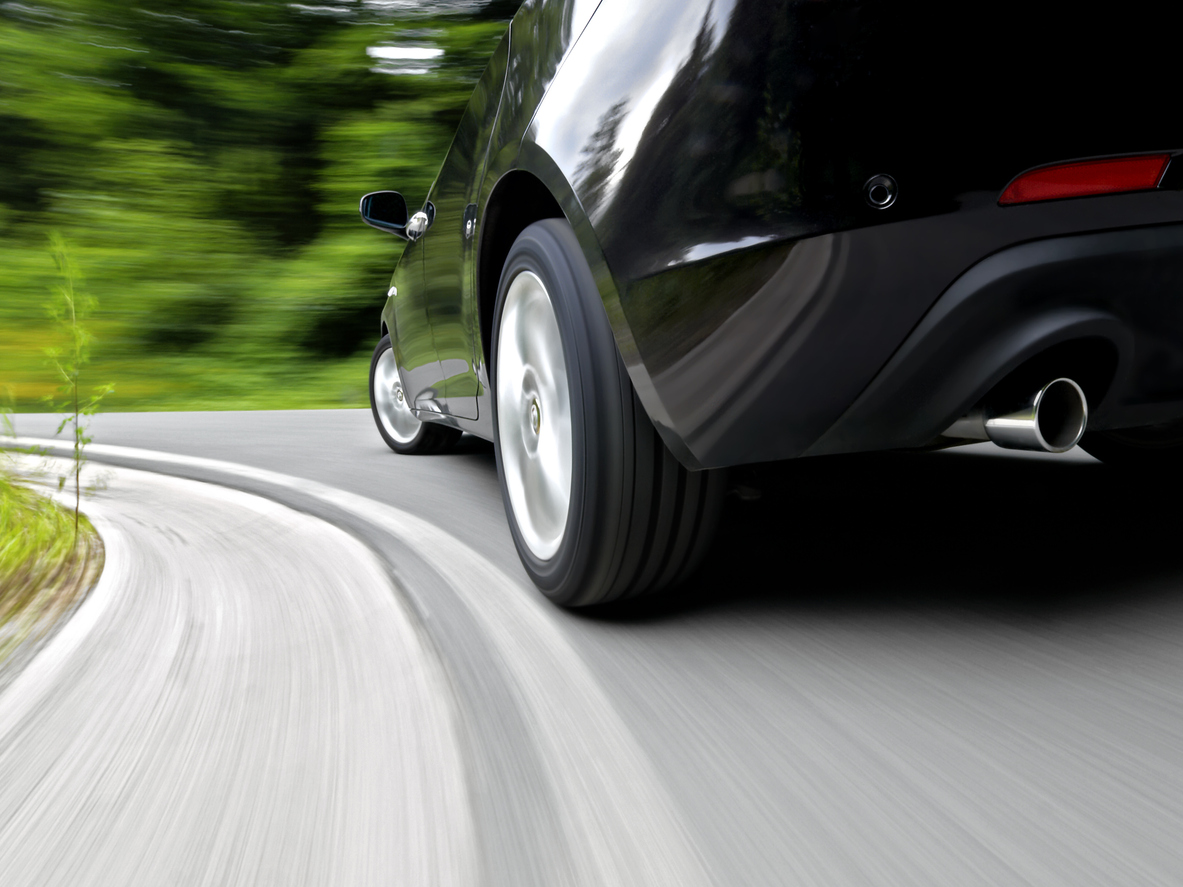 Low angle, rear wheel motion blur shot of a sports car driving fast in a curve