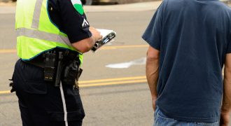 a police officer talking to a man while writing a report