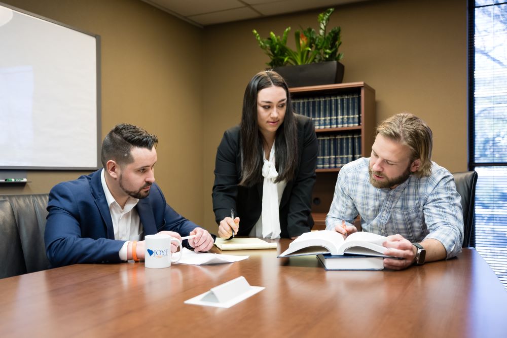 3 attorneys sitting at a table discussing a case