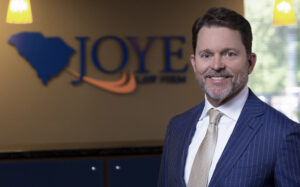 Mark Joye standing in front of a Joye Law Firm sign