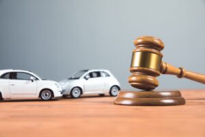 A court gavel sits beside toy cars on a table, symbolizing a car accident case.