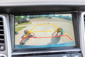 Children seen in a rear view backup camera drawing with chalk.